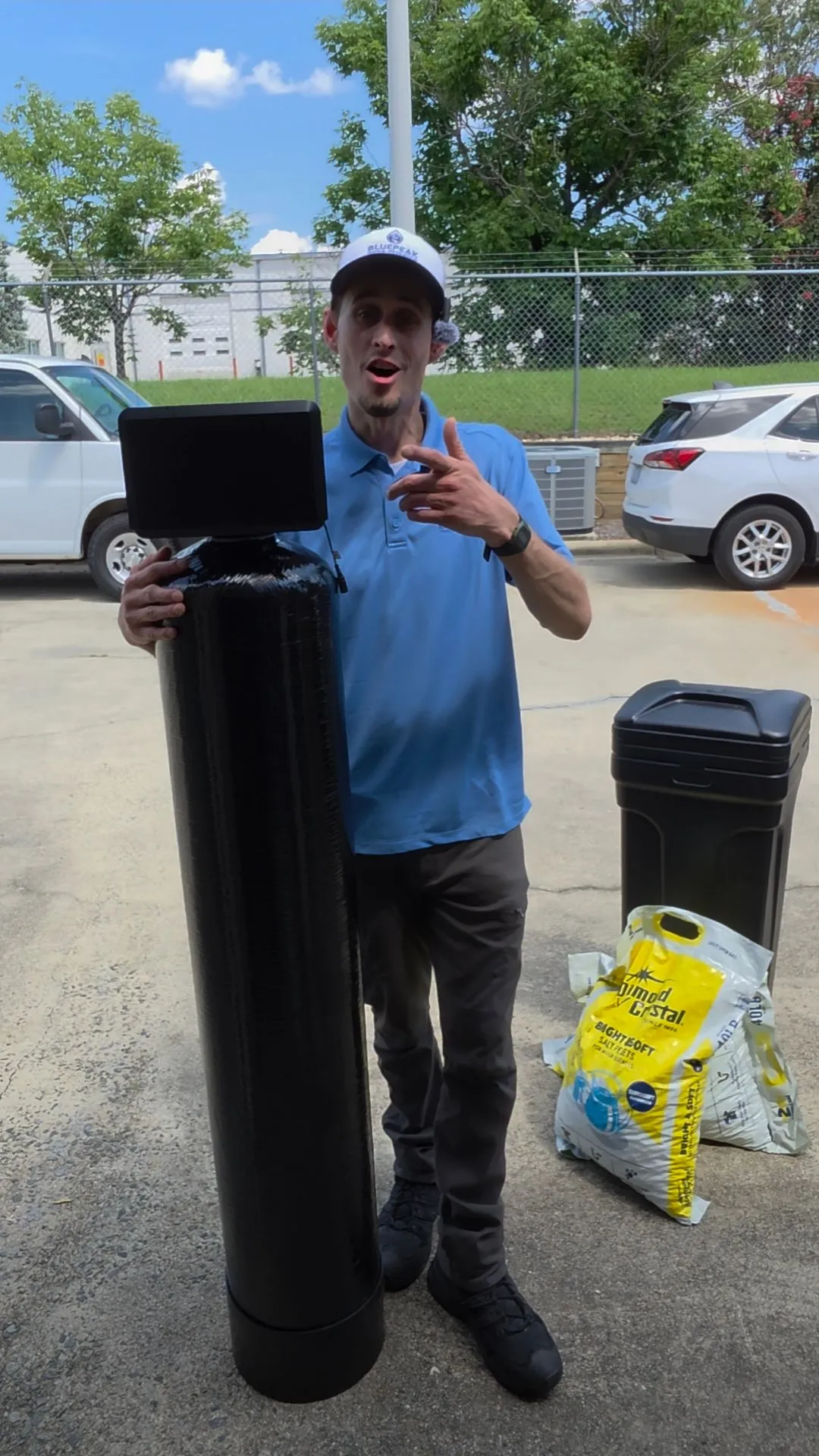 Branden holding a softener tank beside a brine tank while explaining a system to a customer.