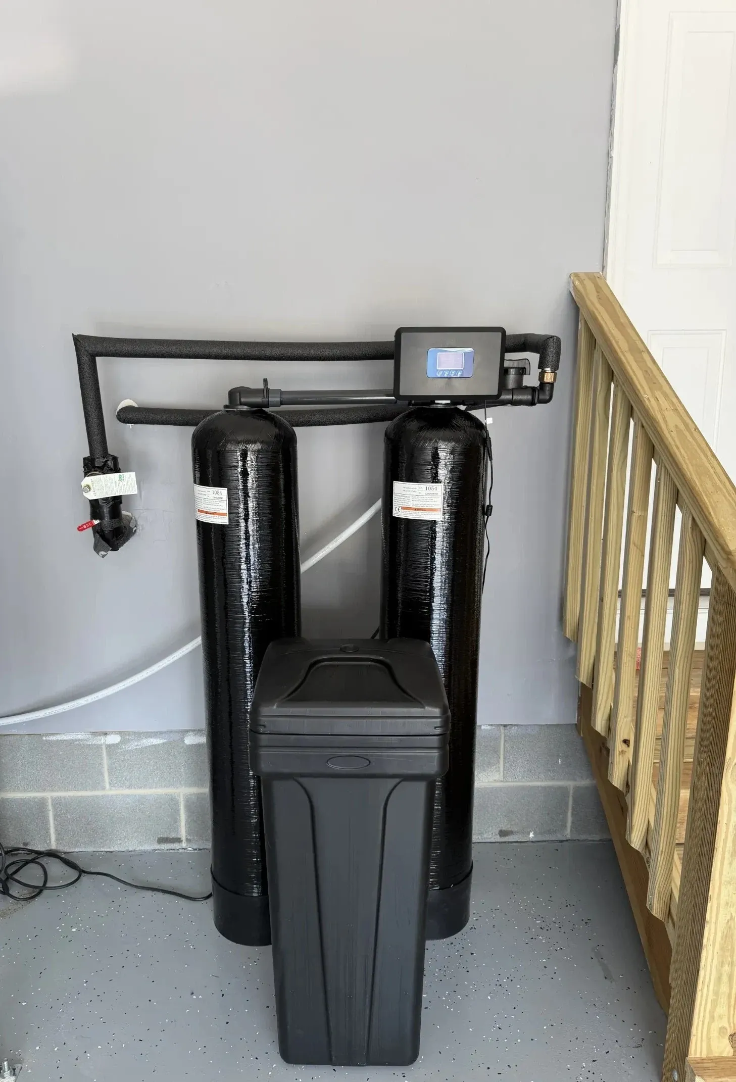 BluePeak Dual Tank system in a Durham garage: two black media tanks and a brine tank beside the garage steps