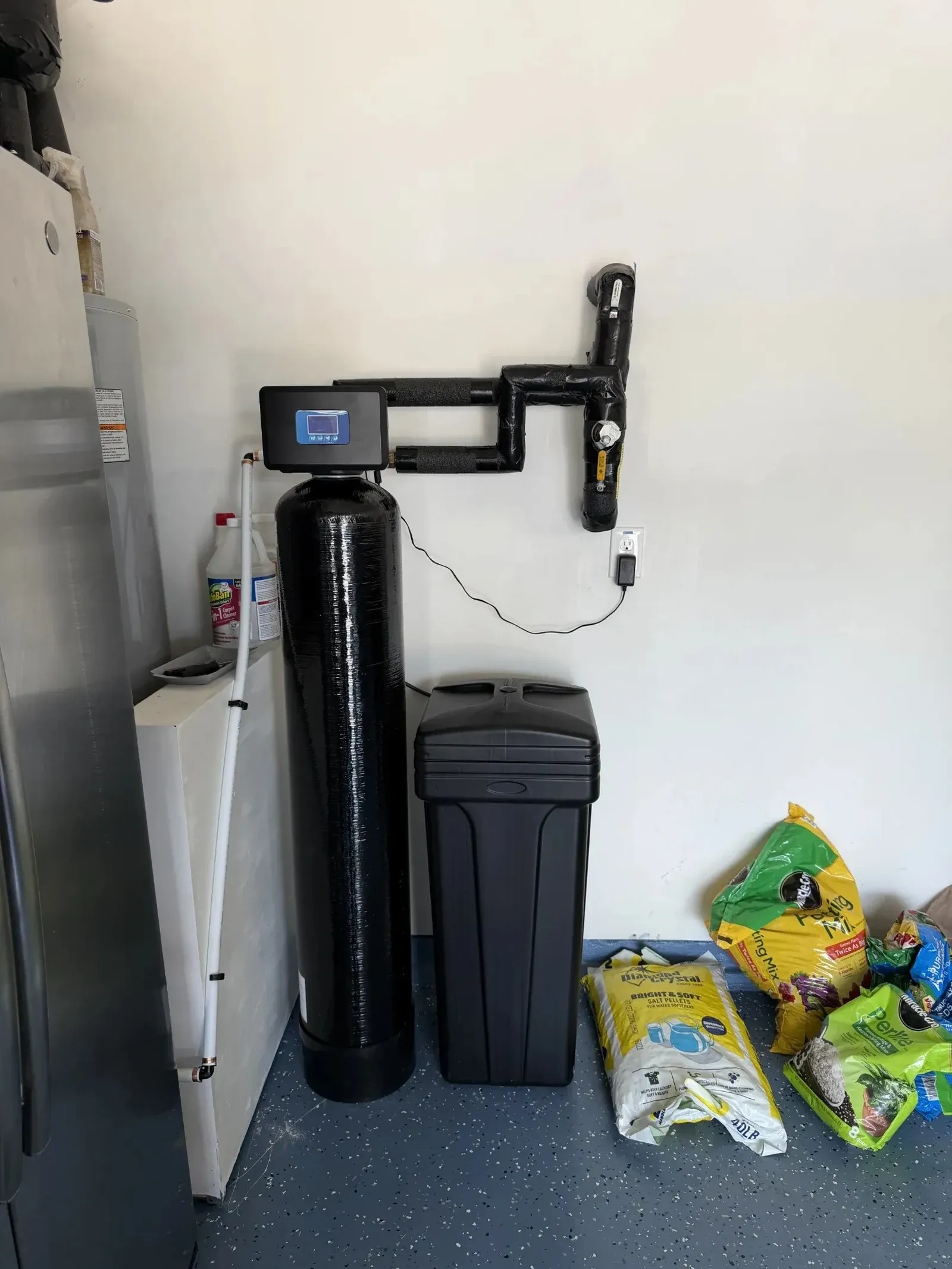 BluePeak Single Tank XL with its brine tank and wall-mounted plumbing loop in a Cary garage